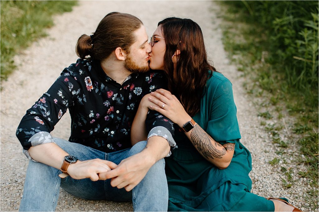couple sitting down kissing on dirt road