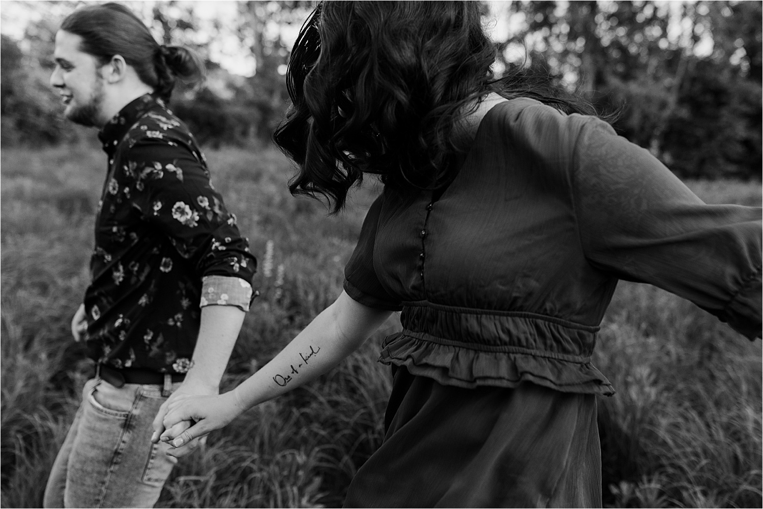 black and white photo of couple holding hands running in field