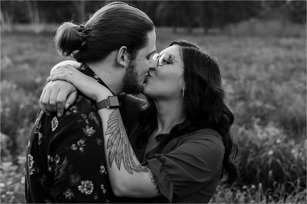 black and white photo of couple kissing in field