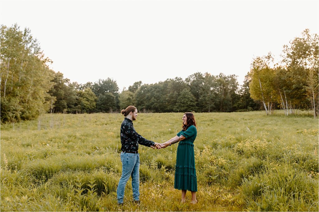 couple holding hands in field 