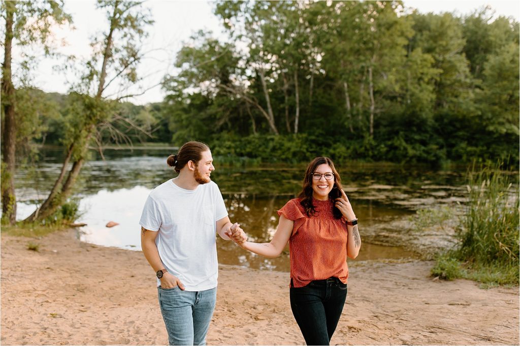 couple holding hands smiling on beach
