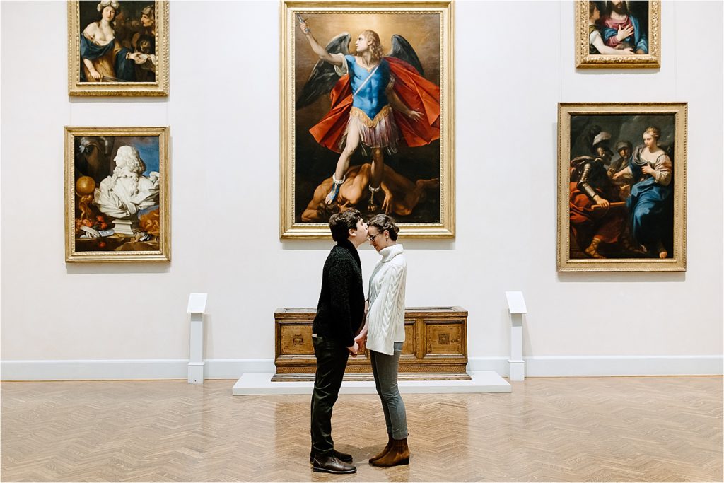 Couple standing facing each other man kissing woman's forehead in Minneapolis Institute of Art