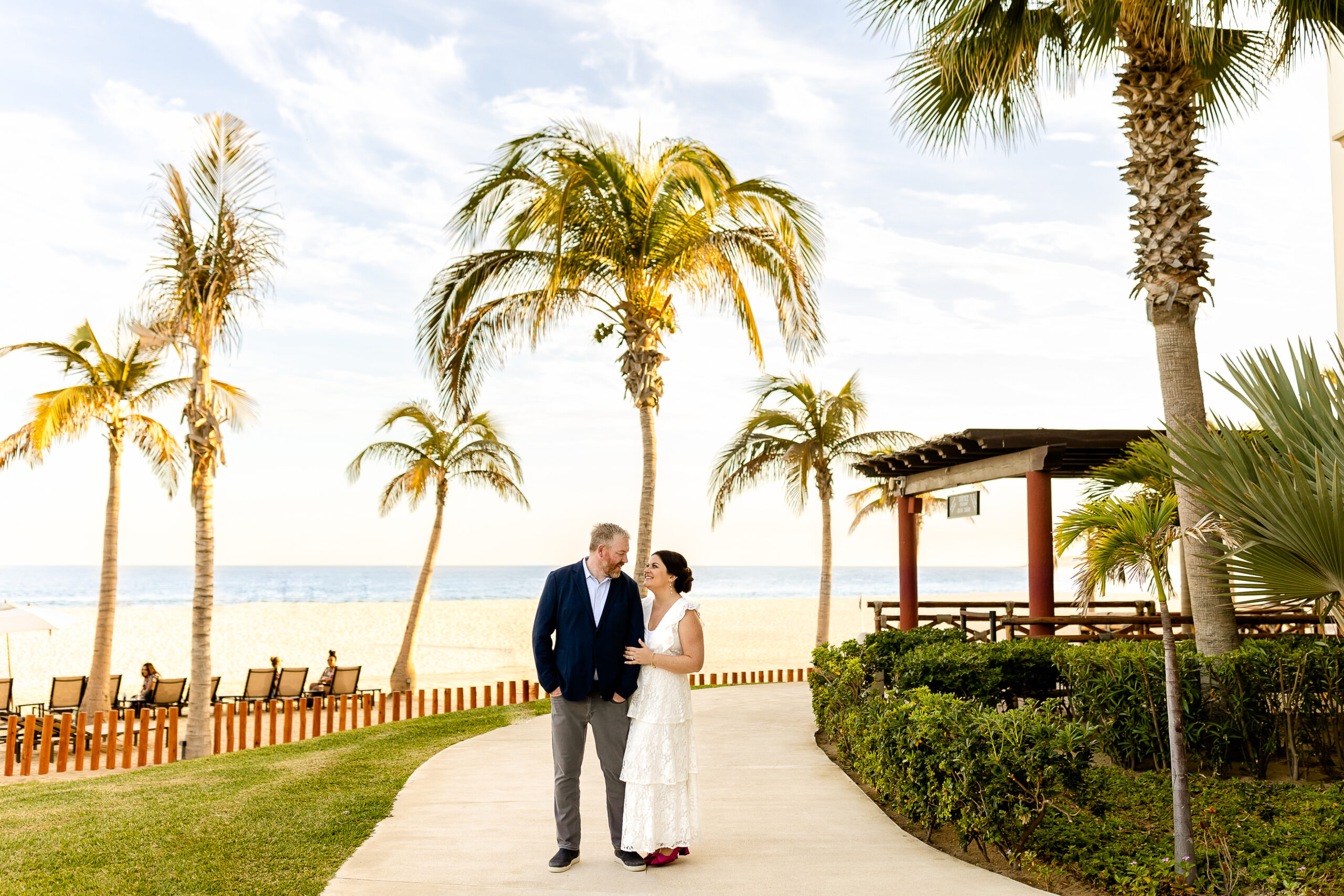 Couple smiling while looking at each other by the beach with palm trees