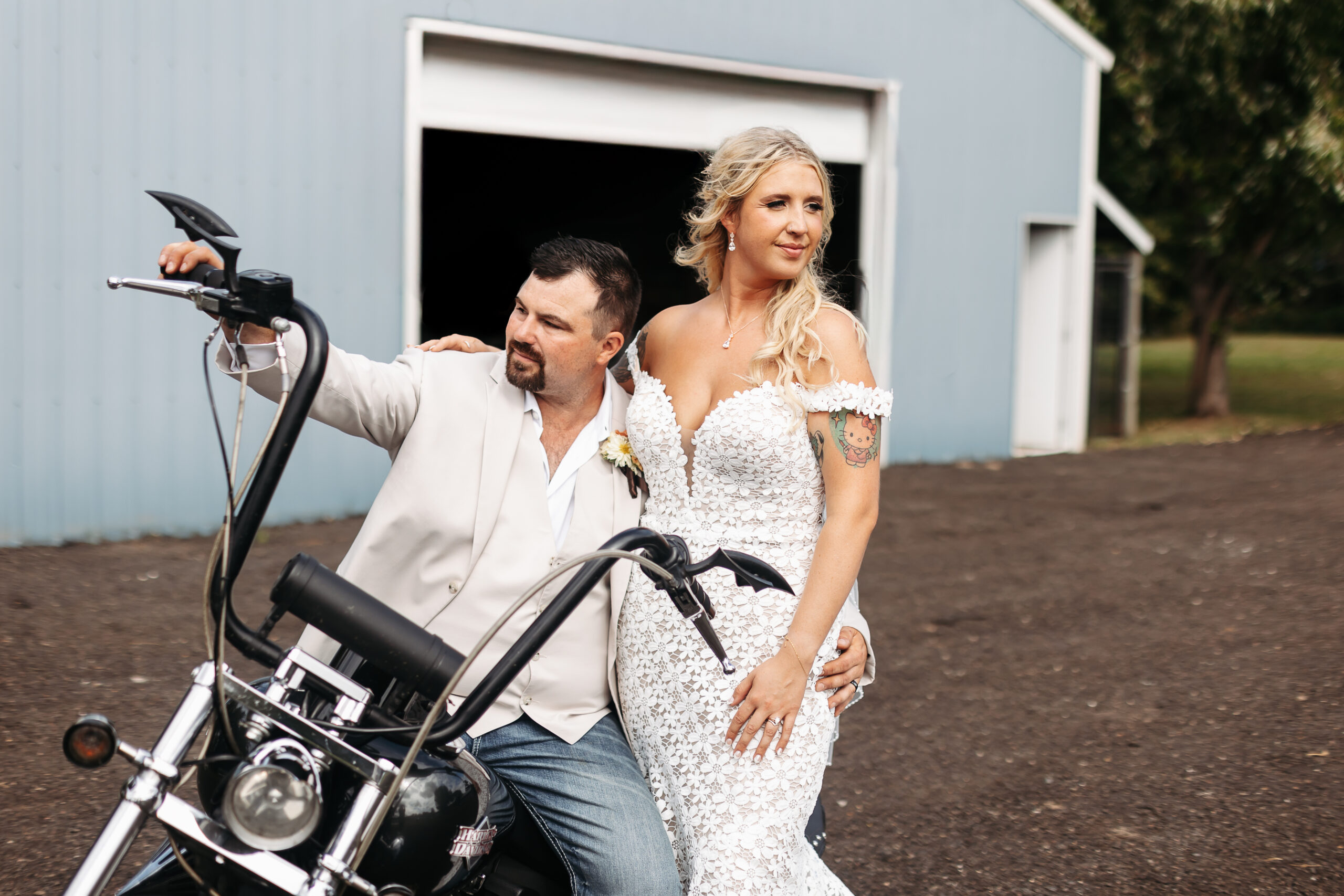 Man sitting on motorcycle with woman in wedding dress standing next to him