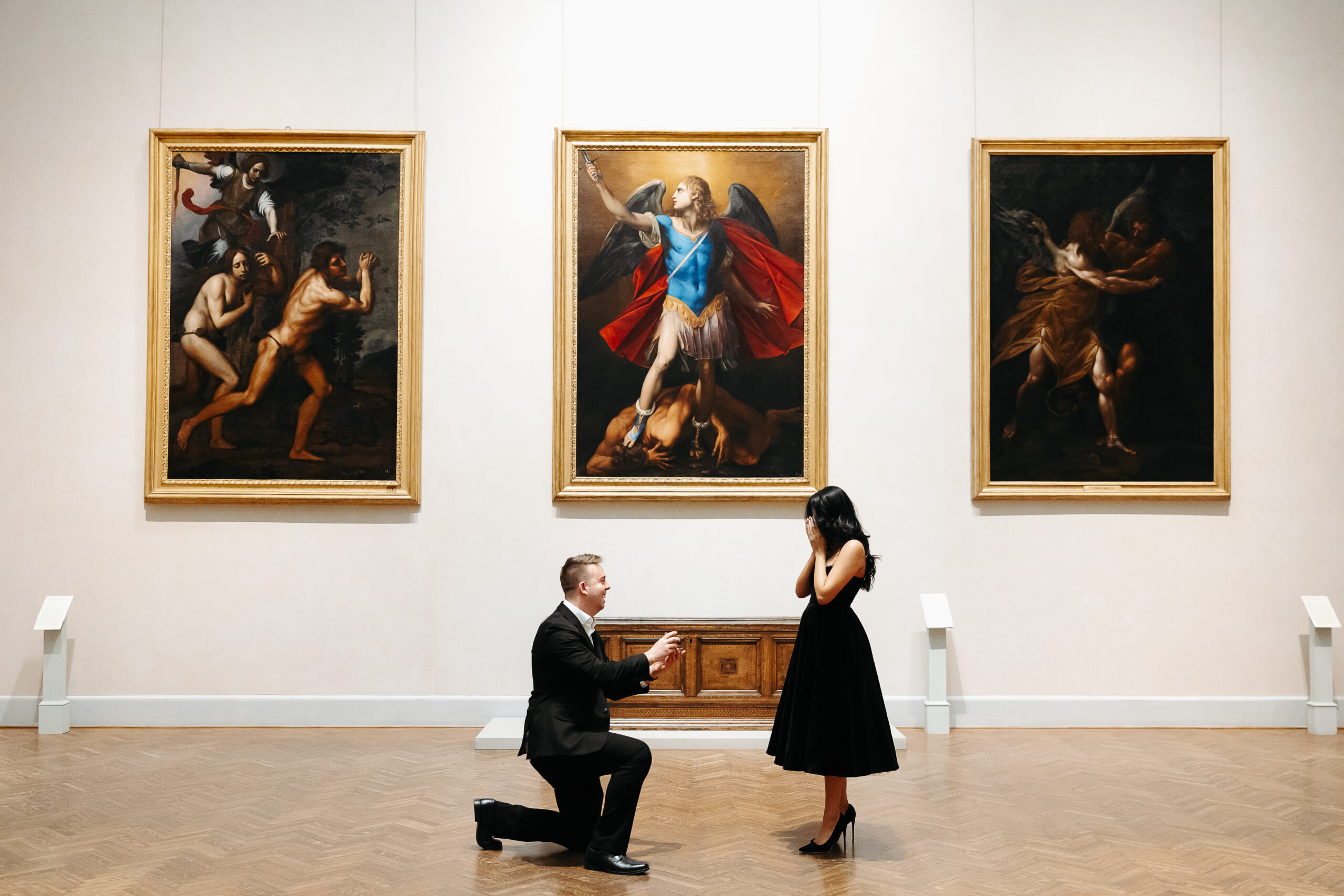 man on bended knee holding engagement ring in front of woman