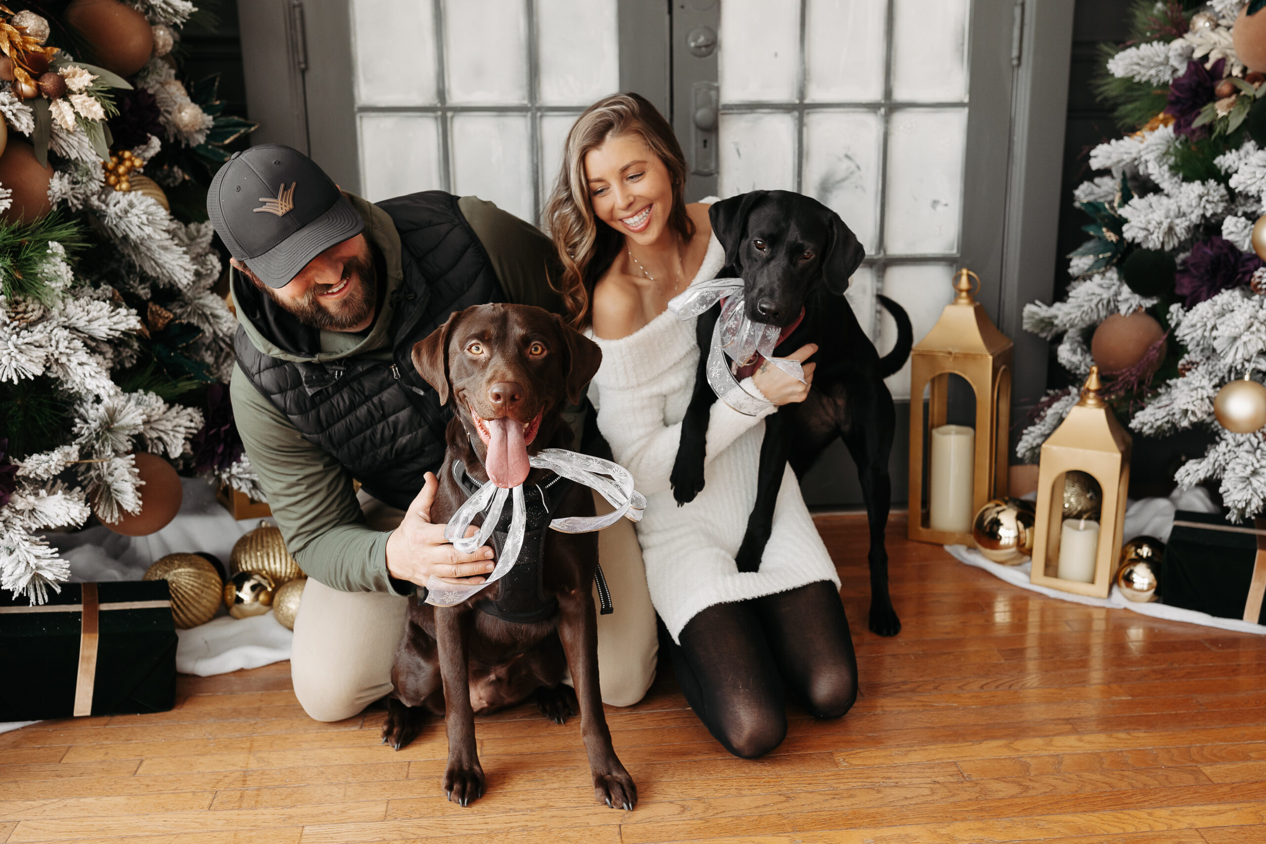 man and woman cuddling with dogs and smiling